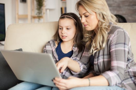 Mother and daughter using laptop with wireless technology for surfing on the internet.
