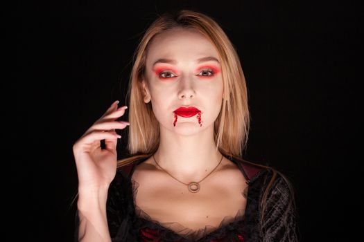Portrait of beautiful vampire woman over black background. Attractive vampire.