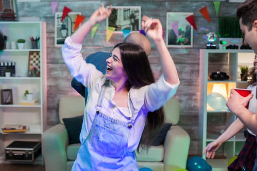 Excited young woman dancing at a party with her friends on disco music.