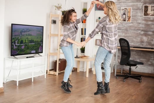 Happy young mother and daughter jumping around in living room. Beautiful childhood.