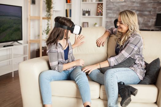 Young mother looking at her little girl having fun with virtual reality headset. Modern motherhood.