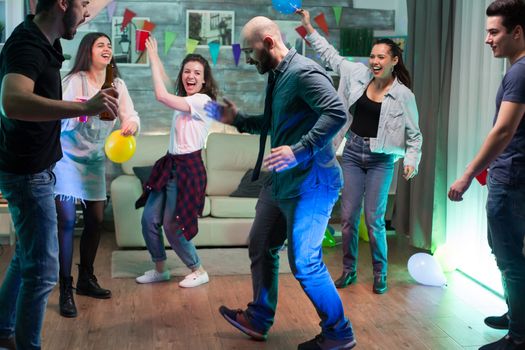 Group of friends cheering up while handsome man doing robot moves at the party.