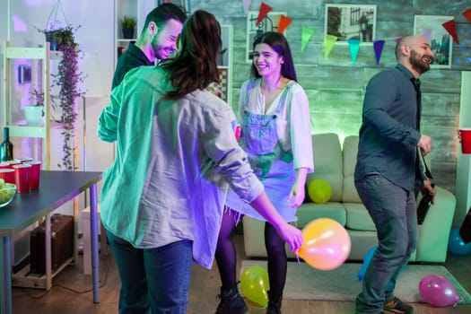 Young woman laughing at a party with her friends and dancing on funky music.