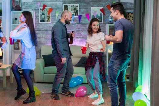 Cheerful young woman having fun and dancing with her friends at a party listening funky music.