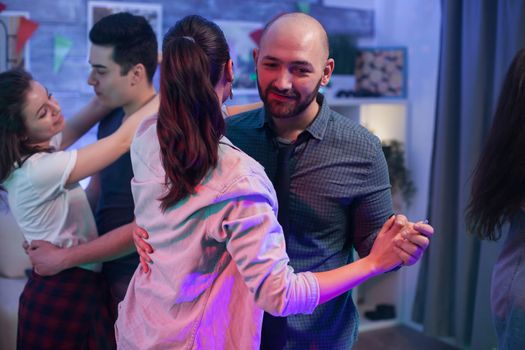 Bald man dancing with his woman at friends party.