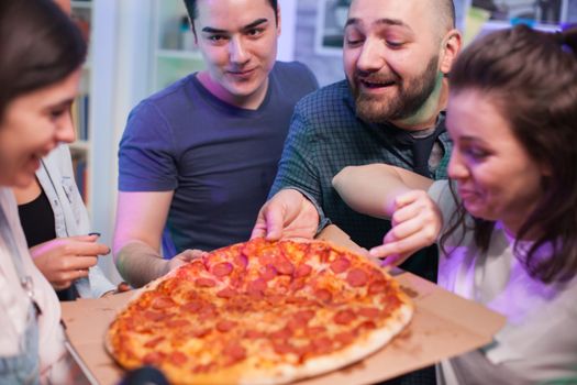 Close up friends at a party excited about delicious pizza. Friends having fun.