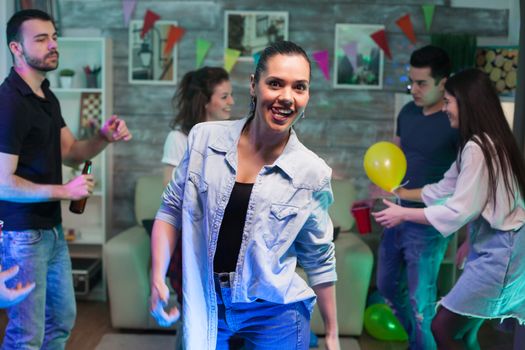 Joyful young woman with a big smile looking at the camera while partying with her friends.