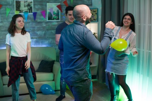 Gathering of young people dancing in an apartment celebrating their friendship.