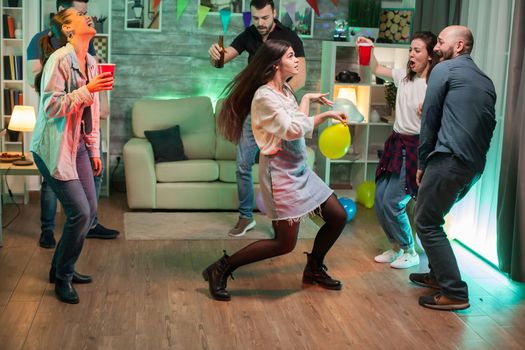 Cheerful young woman with balloon in her hands dancing with her friends at a party.