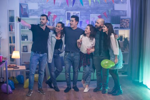 Group of young people taking a selfie at a party in an apartment