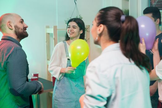 Young woman with a balloon smiling at attractive male at a party.