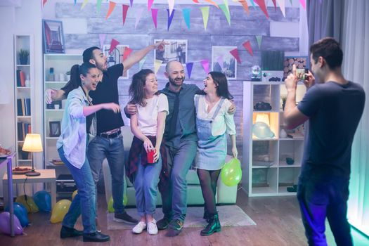 Group of friends celebrating their friendship at a party and taking a group photo.