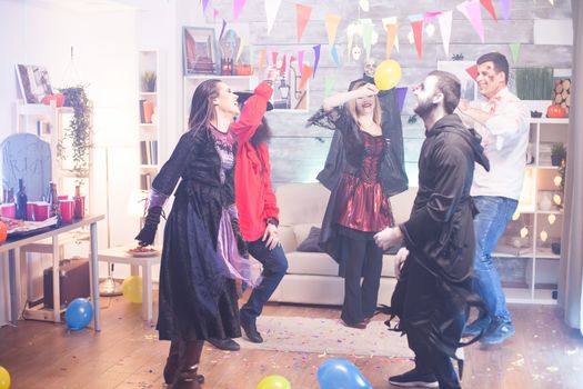 Grim reaper and cheerful witch dancing at halloween celebration. Scary costumes.