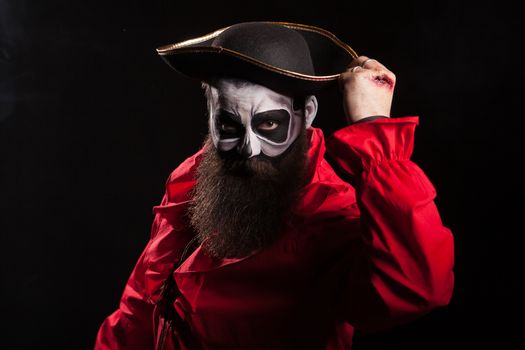 Bearded and spooky medieval pirate with blood on his hands over black background. Halloween disguise.