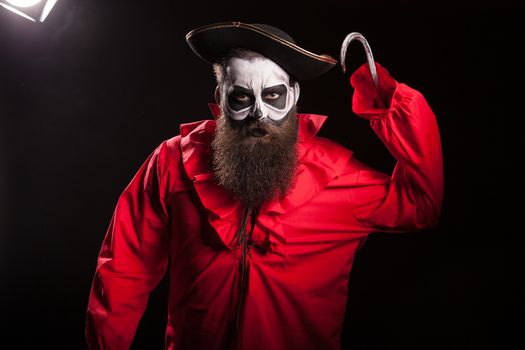 Scary pirate with a hook and long beard over black background. Halloween outfit.