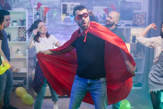 Man in red cape of superhero dancing with his friends.