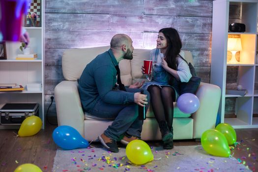 Young couple having an argument sitting on the couch at their friends party.