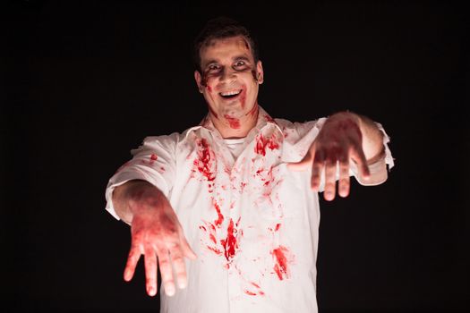 Man dressed up like a zombie covered in blood over black background.