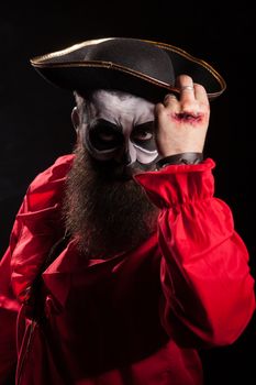 Spooky medieval pirate with blood on his hand over black background. Halloween outfit.