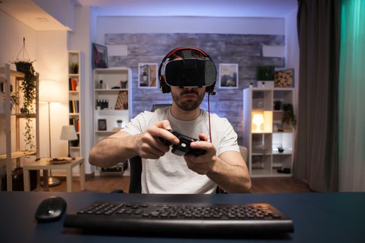 Pov of online shooter gamer wearing virtual reality goggles while using wireless controller.