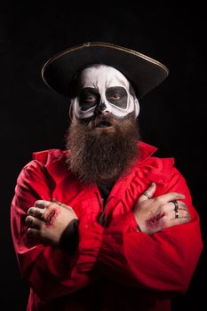 Spooky bearded man with pirate outfit for halloween looking at the camera over black background.