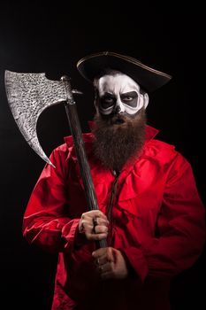 Bearded crazy pirate with his axe over black background. Halloween outfit.