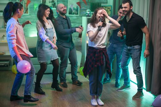 Young woman can't believe she's doing karaoke at her friends party.