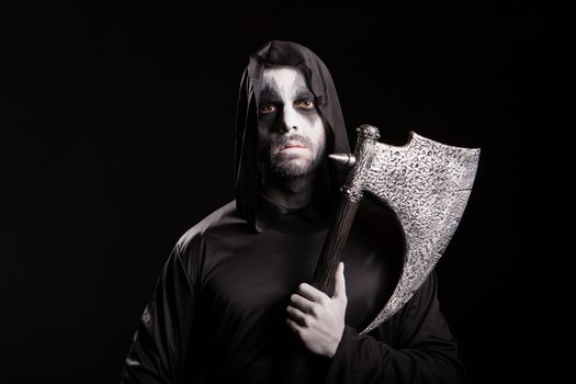 Evil grim reaper with an axe over black background for halloween.