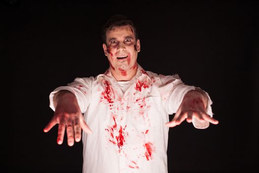 Scary man with bloody hands over black background. Man spreading terror.