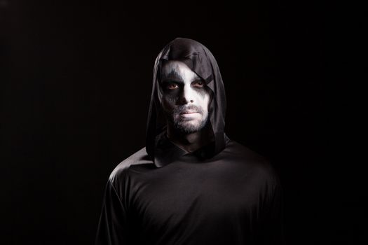 Portrait of man dressed up like angel of death over black background for halloween.