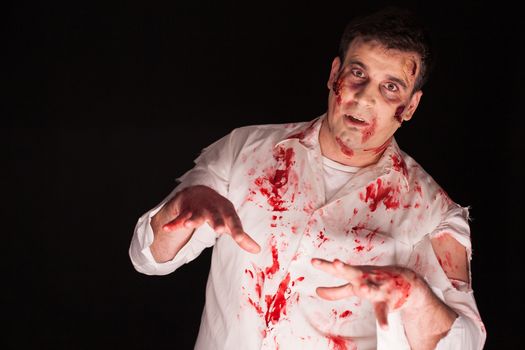 Man wearing a bloody zombie costume over black background for halloween. Creative makeup.
