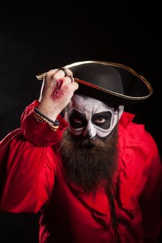 Spooky medieval pirate with hat saying hello isolated over black background. Halloween outfit.
