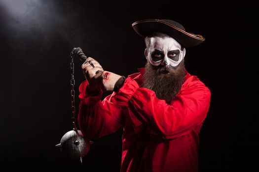 Spooky male pirate with long beard holding a mace over black background. Halloween outfit.