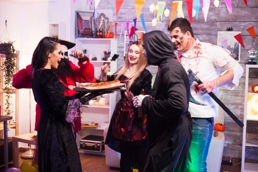 Excited young people about tasty pizza at halloween party.