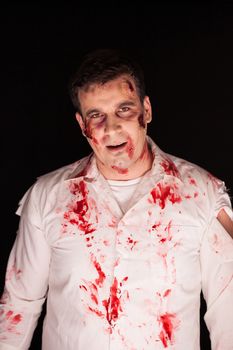 Scary zombie with blood on him after a murder over black background. Halloween outfit.
