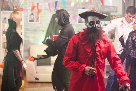 Man dressed up like a medieval pirate holding a beer at halloween party.