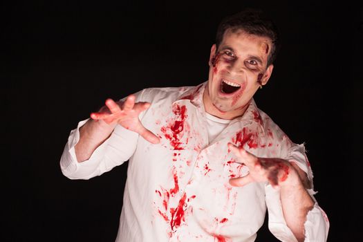 Person possessed by a zombie covered in blood over black background. Halloween costume.