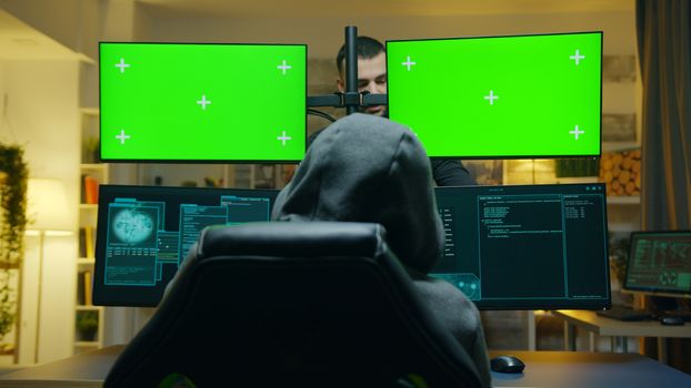 Team of hackers using computer with green screen mockup to steal secret information from the government.