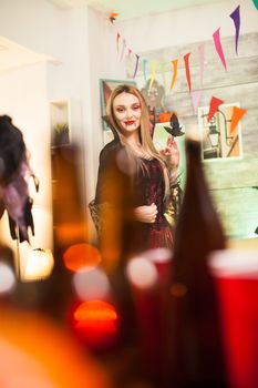 Portrait of beautiful vampire woman with bloody lips at halloween celebration.