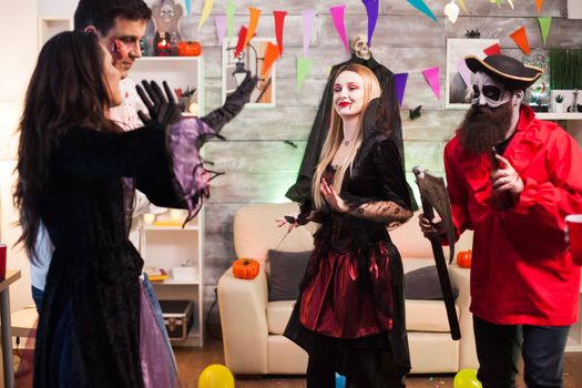 Cheerful woman dressed up like a vampire with bloody lips at halloween party.