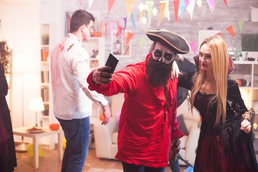 Couple dressed up like a pirate and vampire taking a selfie at halloween party.