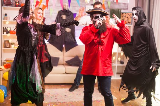 Man in pirate costume doing karaoke at halloween party with his friends.