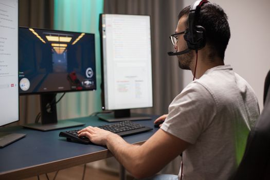 Bearded man having fun while playing shooter games late at night in a room with neon light.