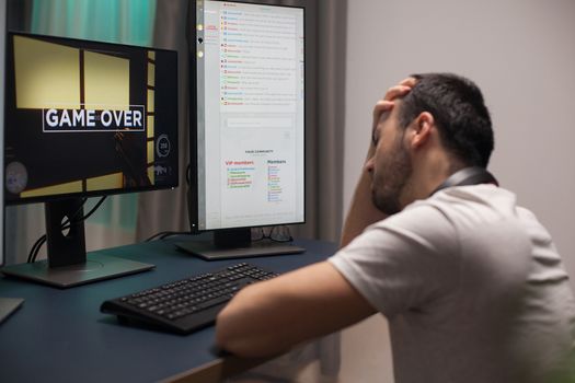 Man covering his face after game over while playing online shooter games.