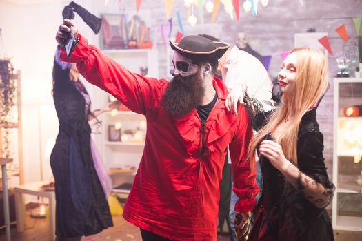 Close friends in pirate and vampire costumes taking a selfie at halloween celebration.