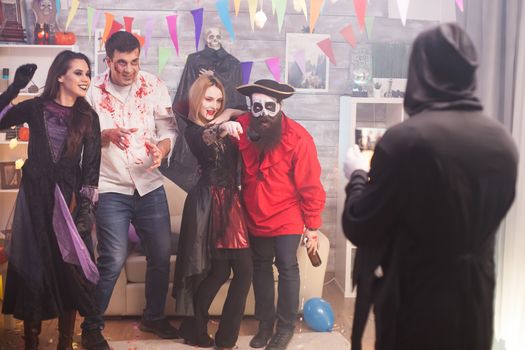 Grim reaper taking photos of pirate and his friends at halloween party.