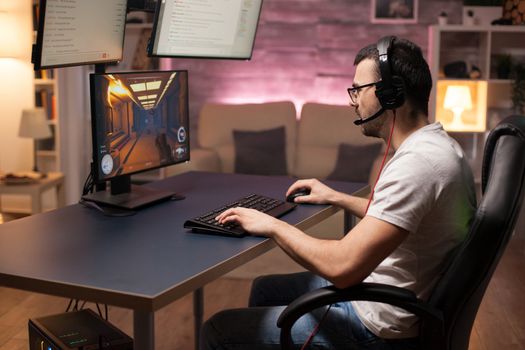 Man wearing headphones talking with his team while playing online shooter games.