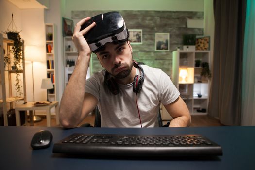 Pov of young man taking off his virtual reality goggles after losing at online games.