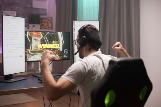 Young man celebrating his victory an online shooter games keeping his fists tight.