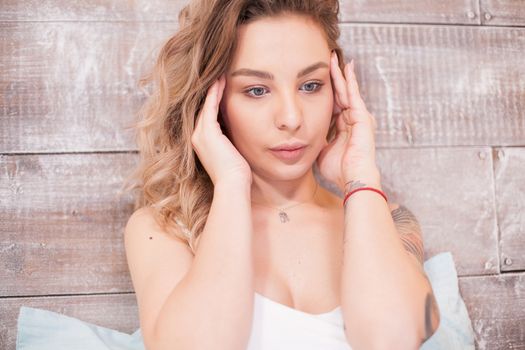 Beautiful woman having a headache at night sitting on bed wearing pajamas .